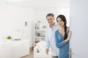 Cheerful couple inviting people to enter in home