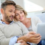 Middle-aged couple relaxing in sofa and using tablet